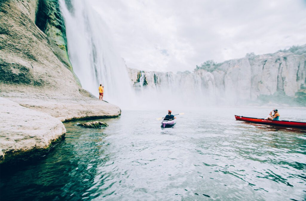 kayakers in front of a waterfall